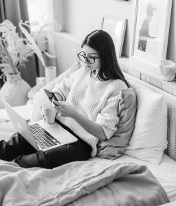 Woman With Laptop And Mug Using Smartphone On Bed 4050412 1.jpg
