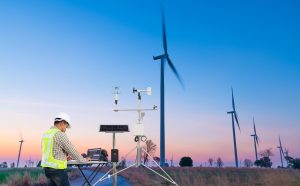 Engineer Using Laptop Computer Collect Data With Meteorological Instrument To Measure The Wind Speed, Temperature And Humidity And Solar Cell System On Wind Turbine Station, Smart Agriculture Concept